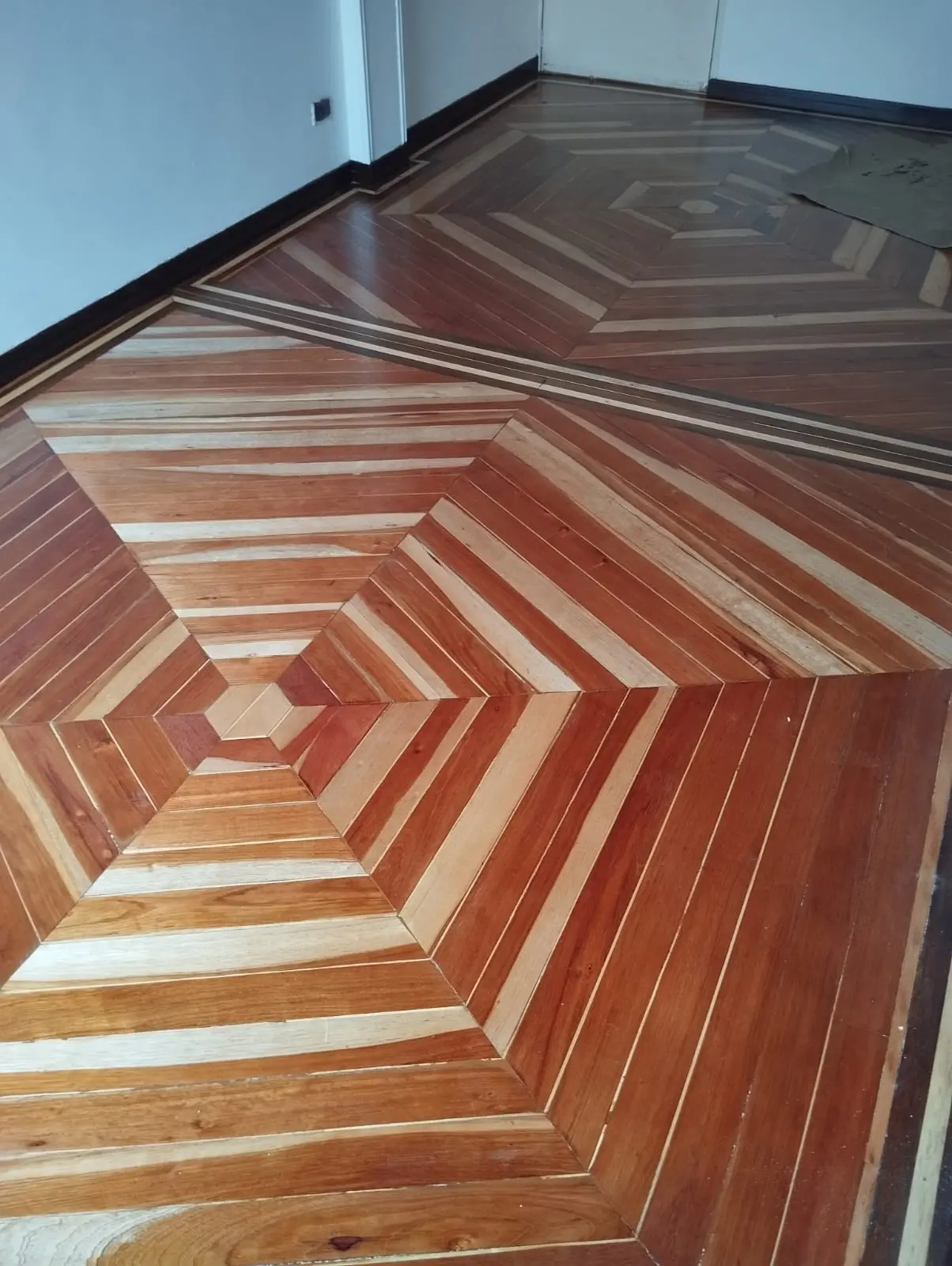 Piso de madera con diseño geométrico restaurado y acabado uniforme